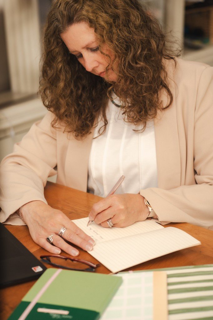 Ally — counsellor and ex-teacher — writing reflectively in a journal at her desk