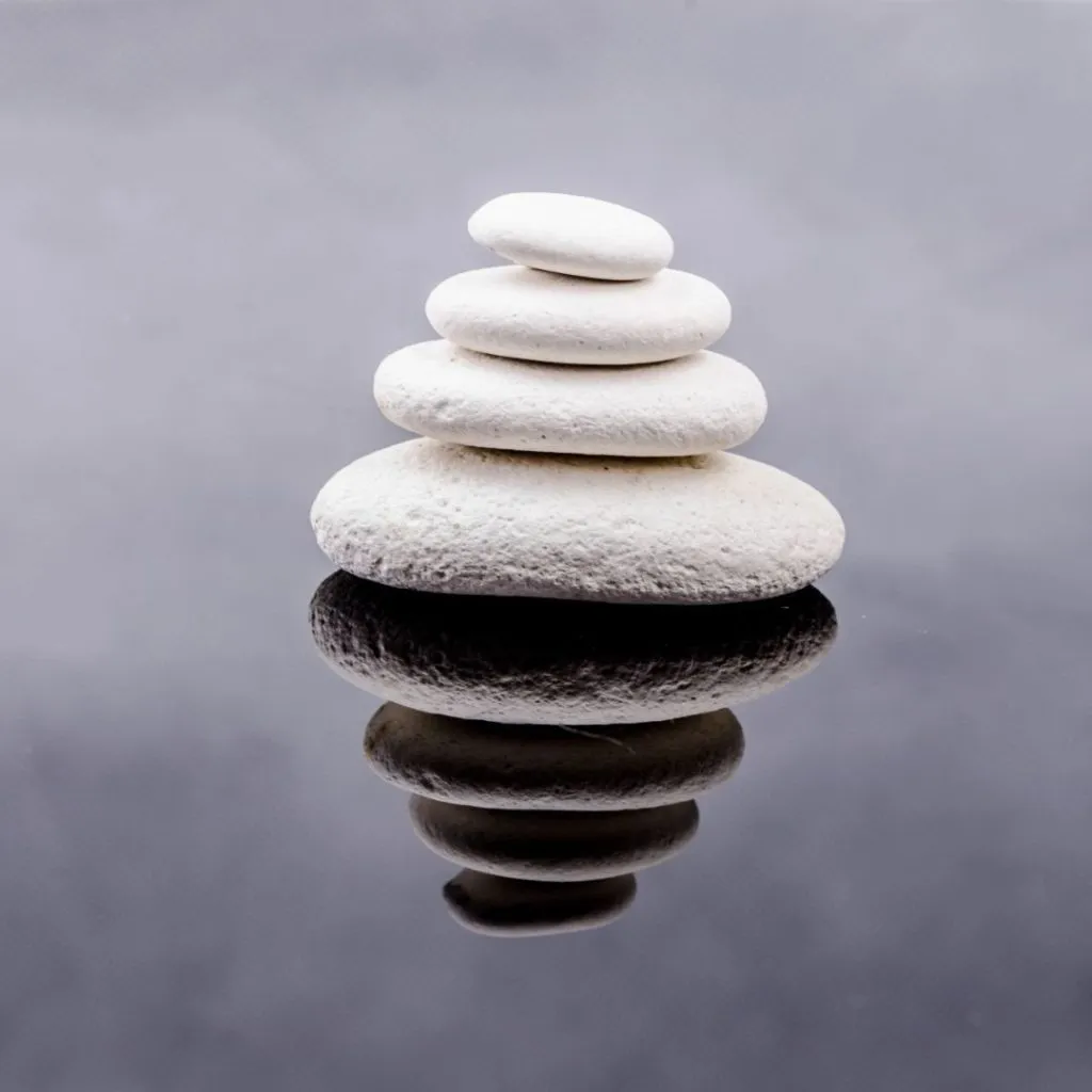 Smooth stones stacked in still water — a quiet moment of grounding